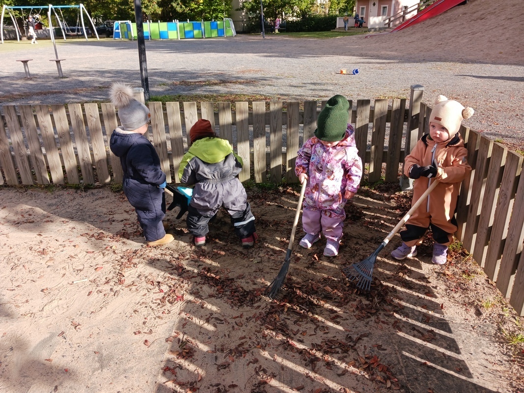Lapset haravoivat pihalla lehtiä.
