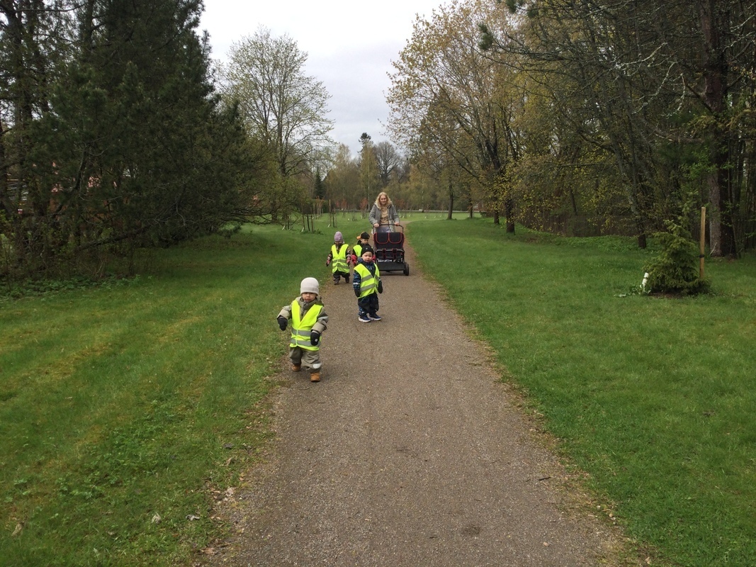 Lapset ovat kävelyllä puistossa aikuisten kanssa.