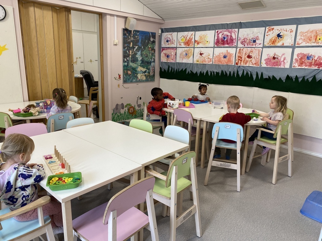 Lapset puuhailevat pöytien ääressä.