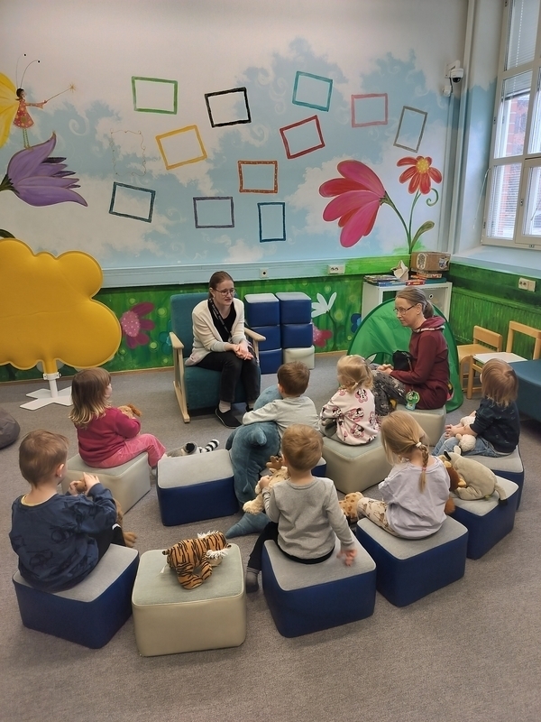 Lapset kuuntelevat kirjastossa satua. Lapset ovat kirjaston satutunnilla.