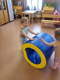 Lapset kierittävät jumppasalissa isoa pehmorullaa.