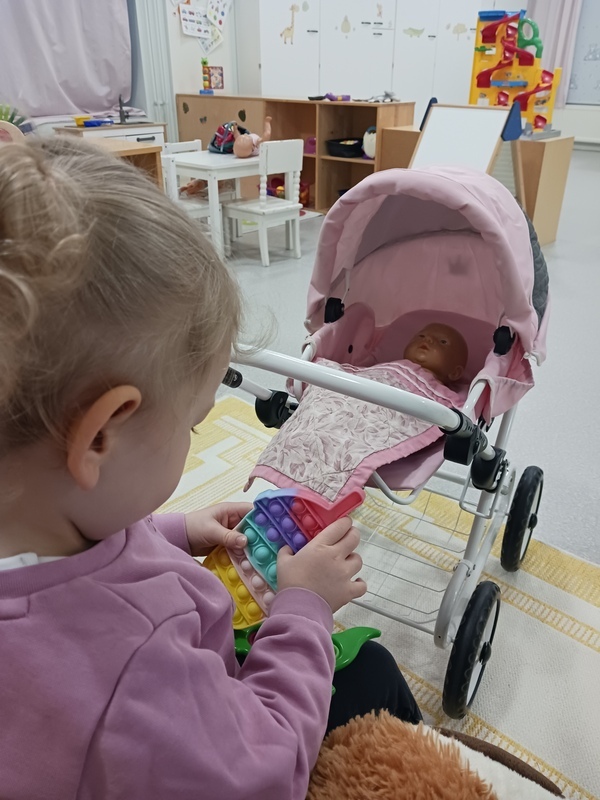 Lapsi nukuttaa nukkea vaunuissa.