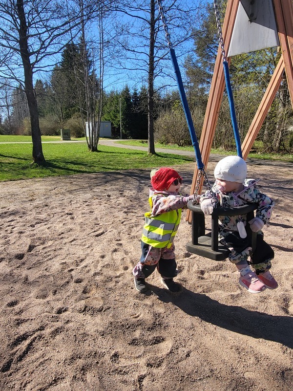 Lapsi antaa keinussa vauhtia toiselle lapselle.