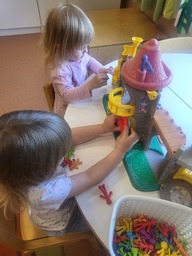 Kaksi lasta leikkii linnalla ja hahmoilla pöydän ääressä.