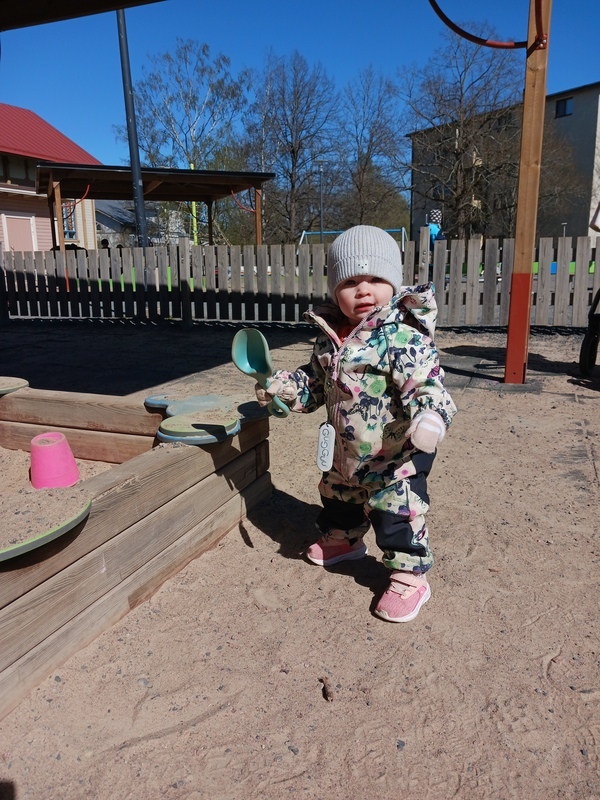 Lapsi ottaa ensiaskeleita lapio kädessään.