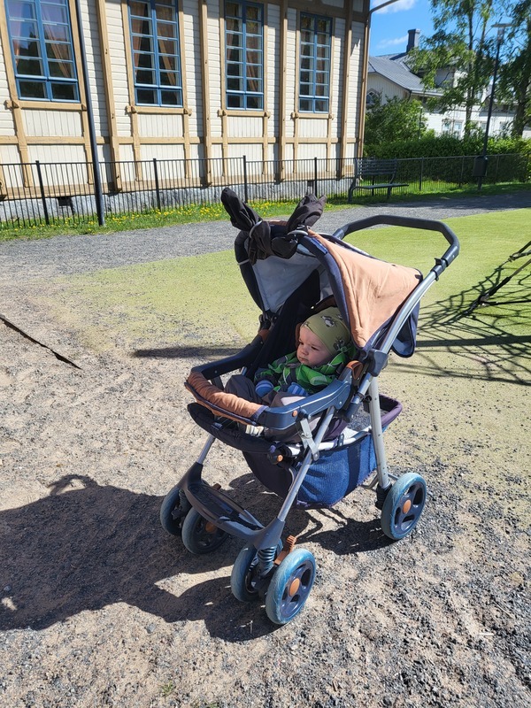 Lapsi istuu rattaissa ja tarkkailee ympäristöä.