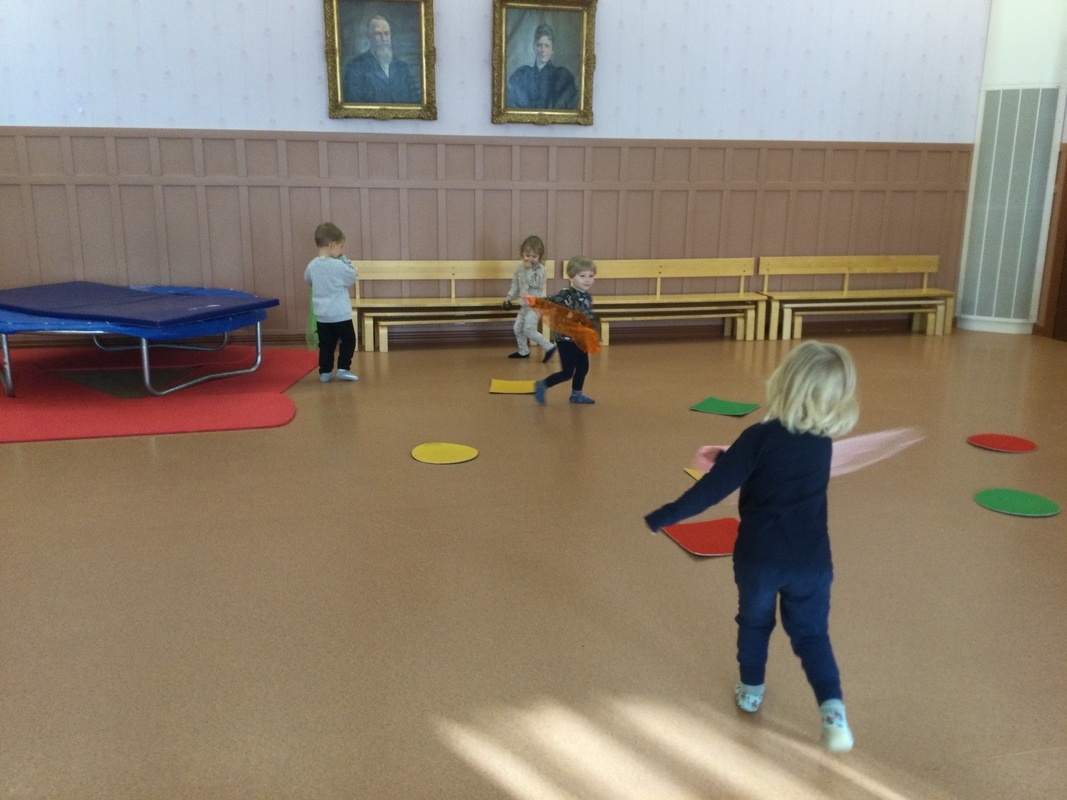 Lapset huivien kanssa satujumpalla, leikkivät leijailevia lehtiä.