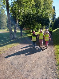 Lapset kulkevat parijonossa hiekkatiellä.