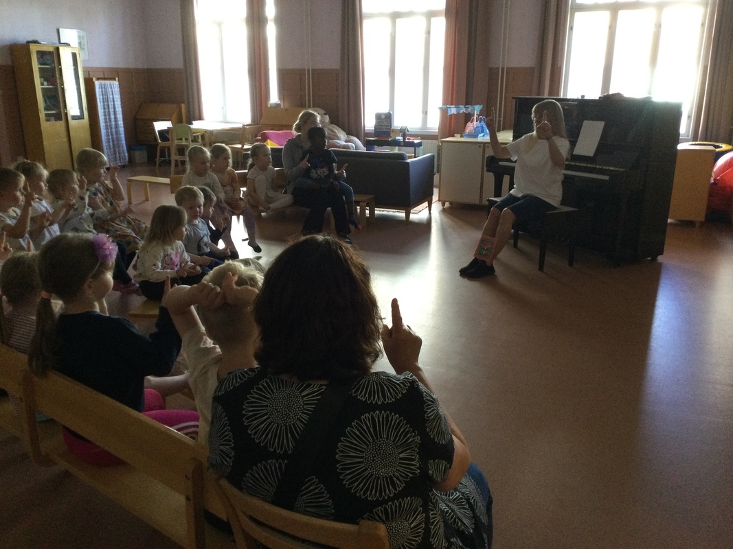 Lapset laulavat salissa penkeillä istuen.