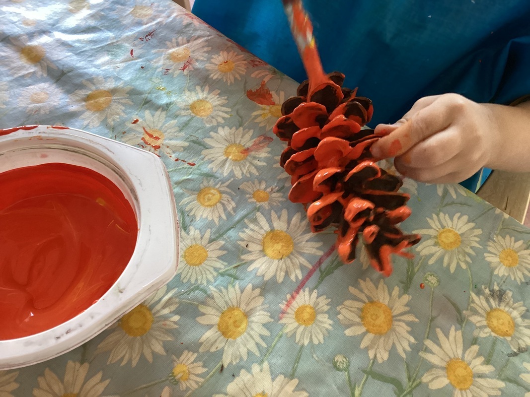 Lapsi maalaa käpyä oranssiksi.