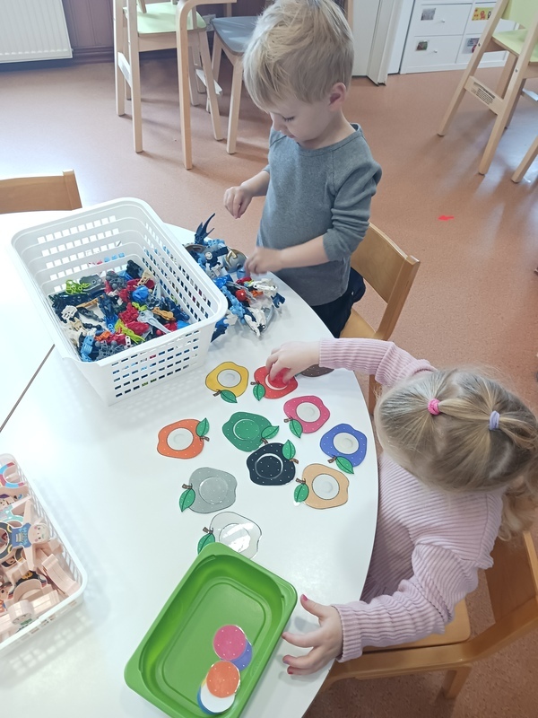 Lapset leikkivät pöydän ääressä bionicleilla ja väritehtävien parissa.