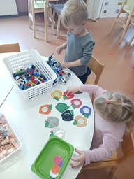 Lapset leikkivät pöydän ääressä bionicleilla ja väritehtävien parissa.