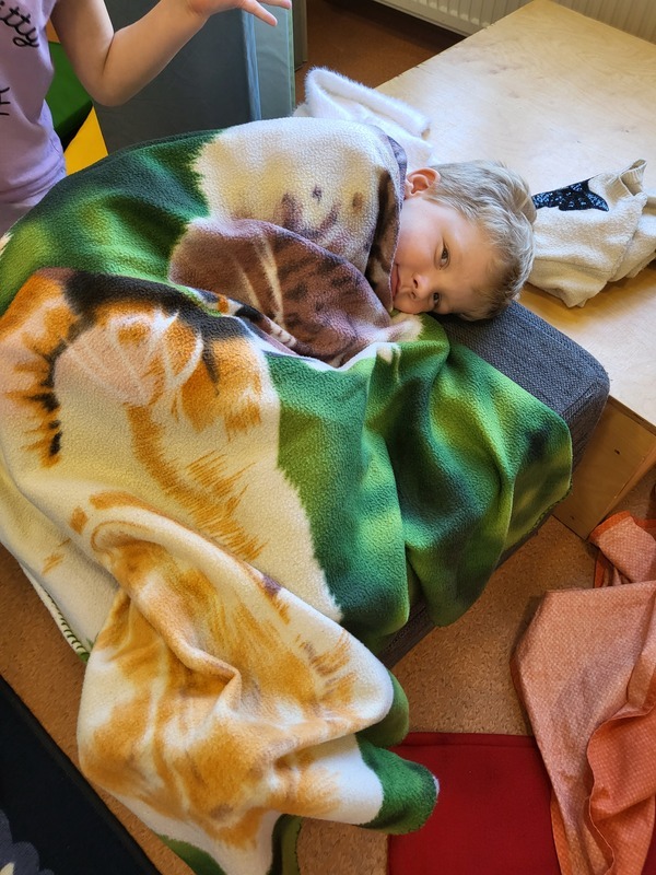 Lapsi lepää leikin lomassa vilttien alla.