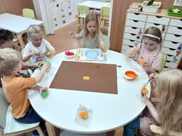 Lapset painavat omenoilla omenoiden kuvia kartonkiin.
