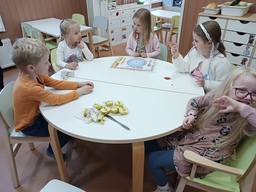 Lapset istuvat pöydän ääressä tutkimassa omenoita.