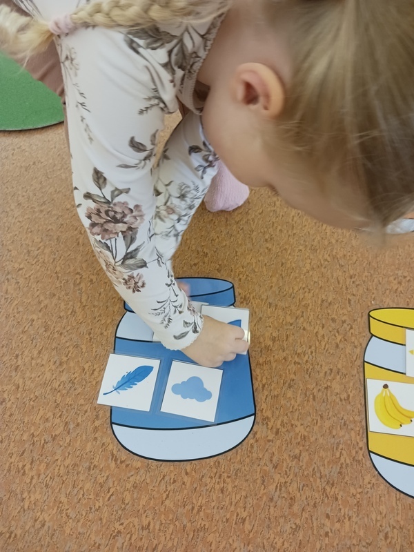 Lapsi laittaa sinisiä kuvia sinisenväriseen purkkiin.