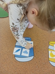 Lapsi laittaa sinisiä kuvia sinisenväriseen purkkiin.