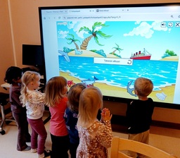 Lapset katsovat smart taululla palapeliä.