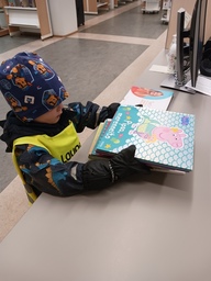 Lapsi lainaamansa kirjan kanssa kirjastossa