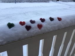 Pieniä jäädytettyjä sydämiä lumisella kaiteella