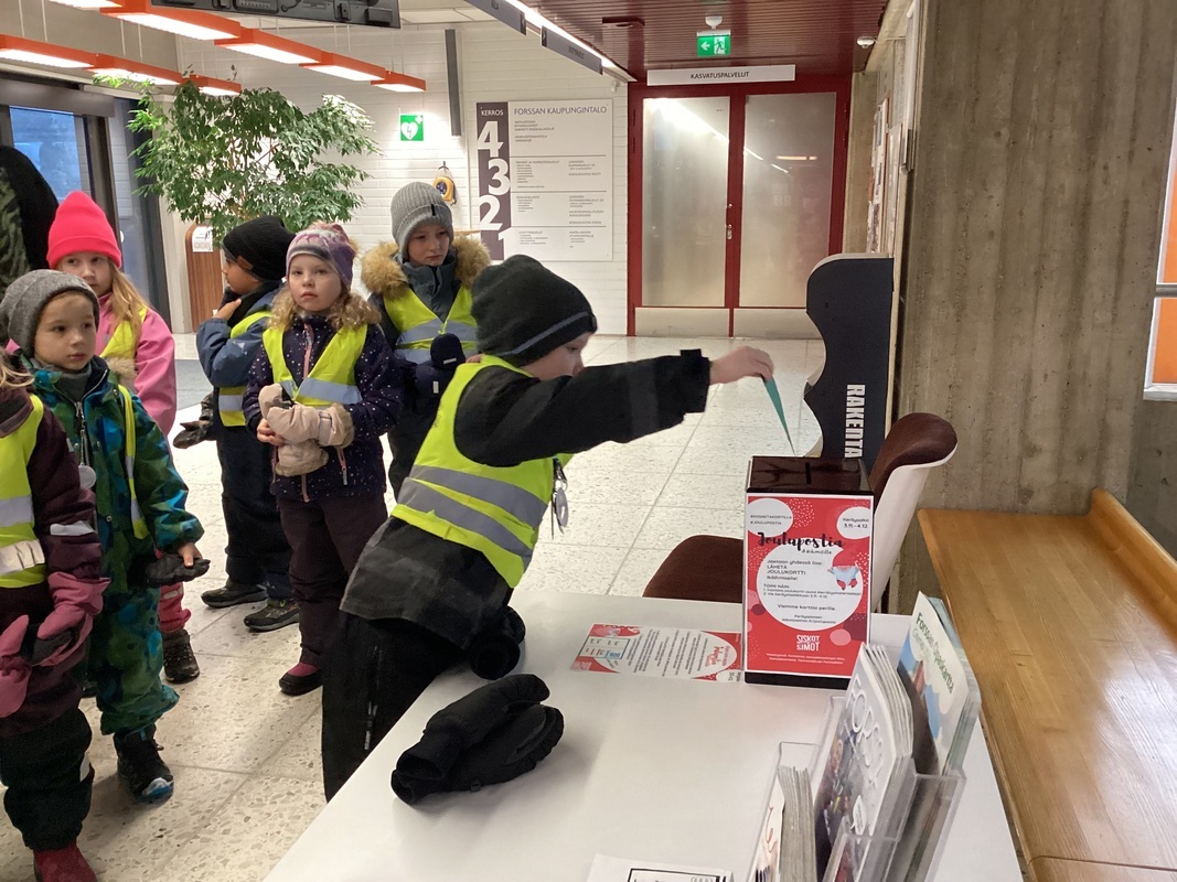 Kaupungintalolle vietiin joulukortteja ikäihmisille. Lapsi pudottaa korttia postilaatikkoon.