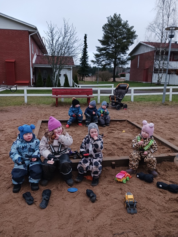 Lapsia istuu hiekkalaatikon reunalla