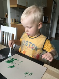 Lapsi maalaa haarukalla mustikanvarpuja.