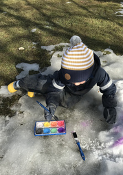 Lapsi maalaa vesiväreillä lunta.