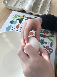 Lapsi rikkoo kananmunan vohvelitaikinaan.