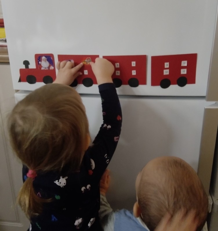Lapsi laittaa tarraa juna-joulukalenteriin