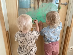 Lapset maalavat ruohoa ikkunaan