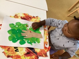 Lapsi liimaa pihlajanmarjoja maalaukseen.