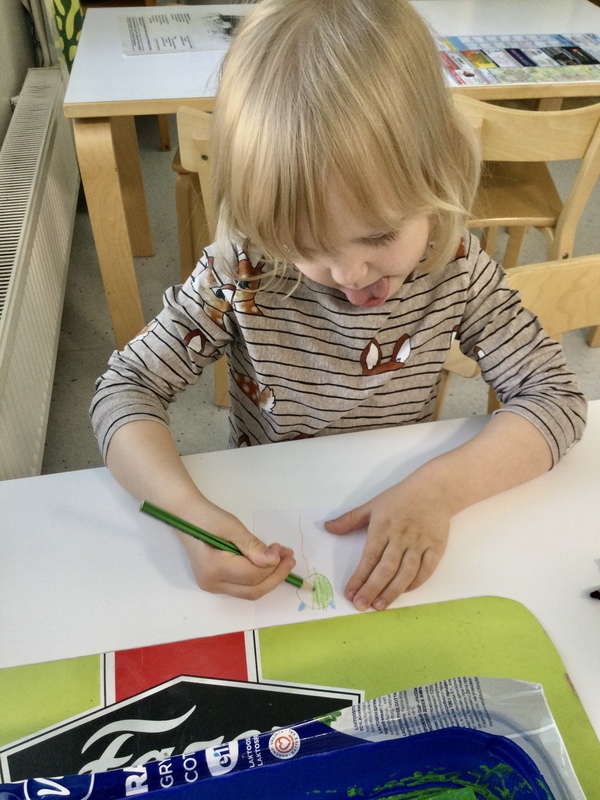 Lapsi piirtää pienryhmänsä Tikkarit-logoa.