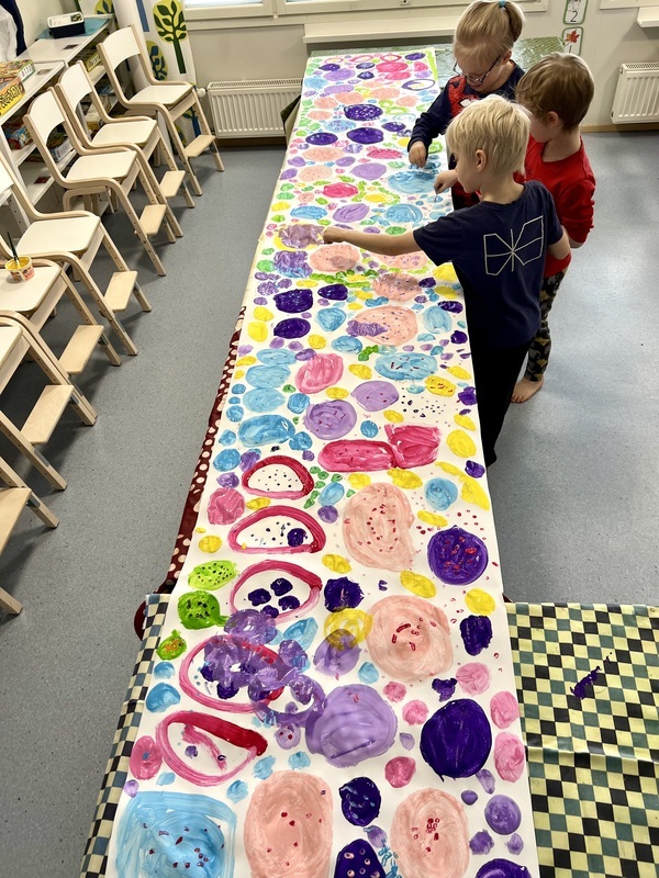 Lapsia maalaamassa värikästä yhteisteosta.