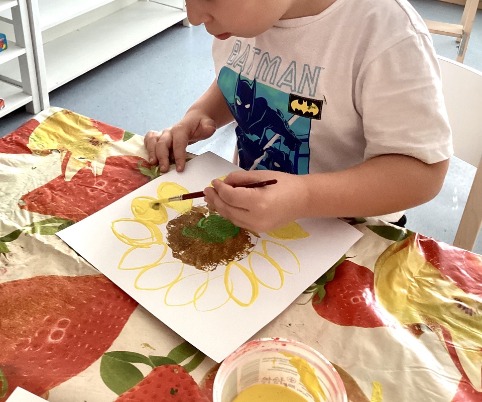 Lapsi maalaa auringonkukkaa.