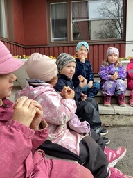 Lapset syövät munkkeja päiväkodin pihalla