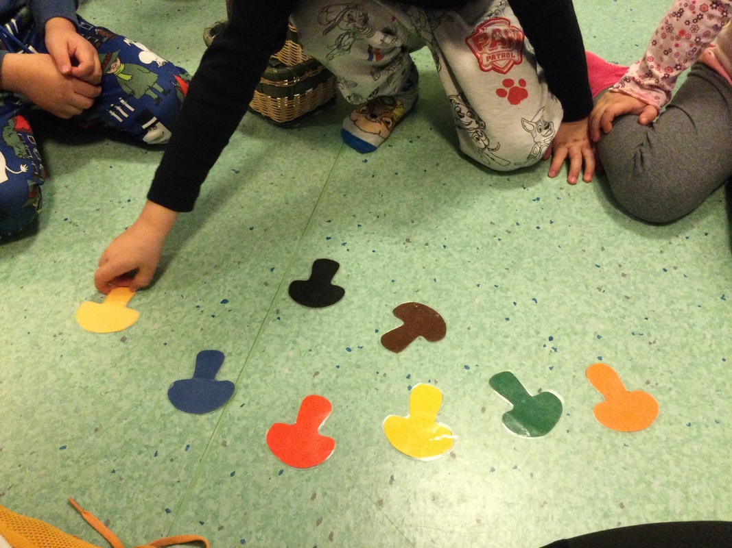 Kuvassa lattialla eri värisiä kartonkisieniä, joita lapset keräävät