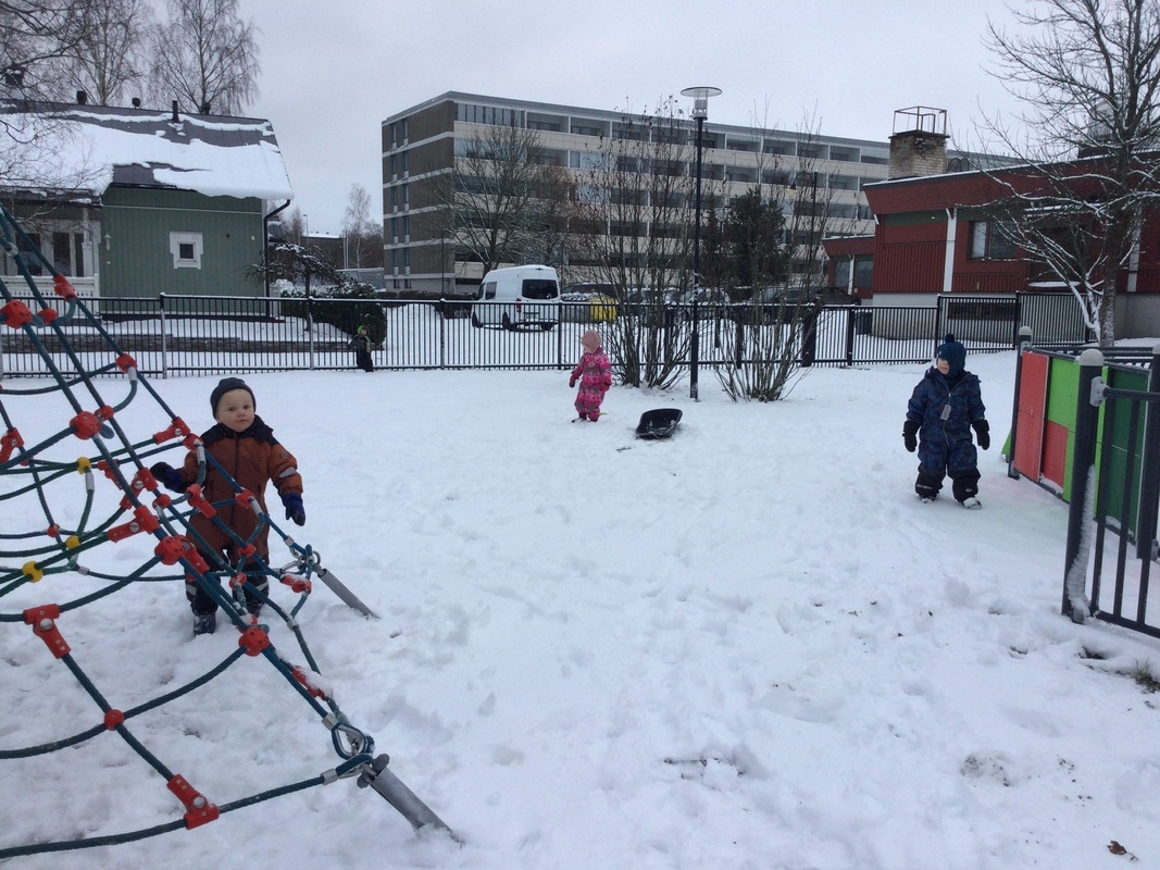 Luminen päiväkodin piha, jossa lapset leikkivät.