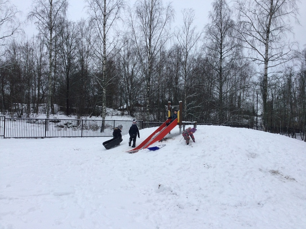 Kuvassa kolme lasta lumisessa mäessä
