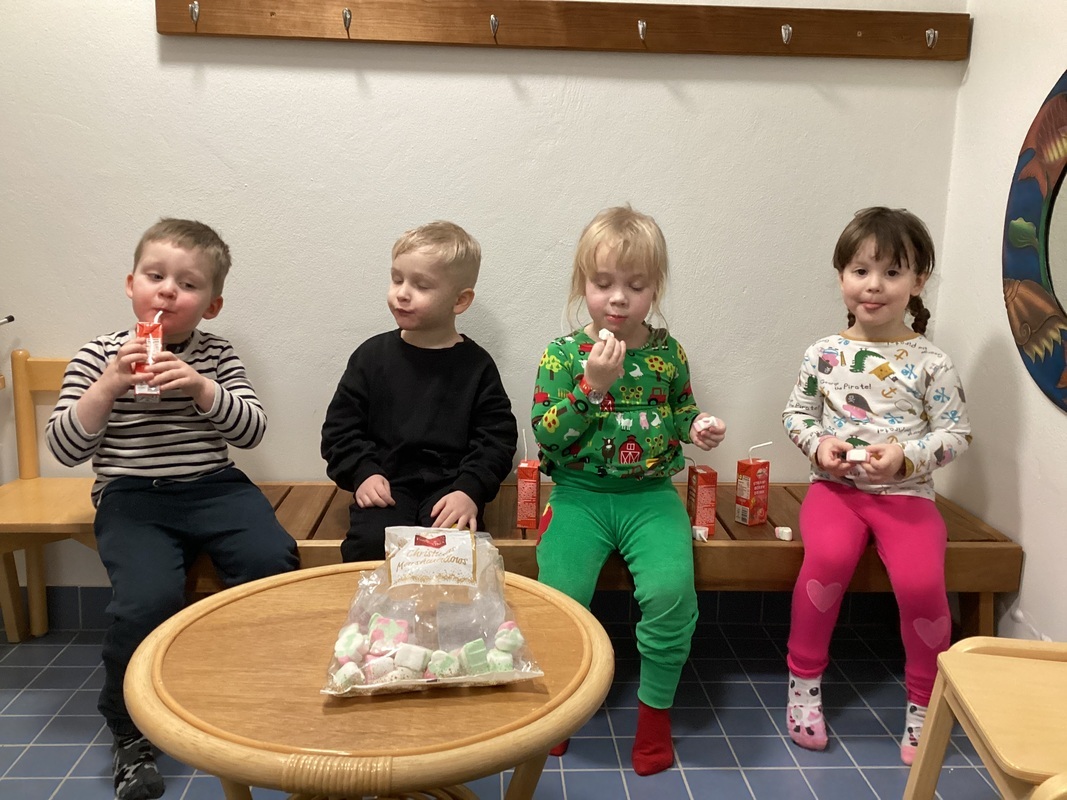 Neljä lasta istuu penkillä ja juovat pillimehua ja syövät vaahtokarkkia.