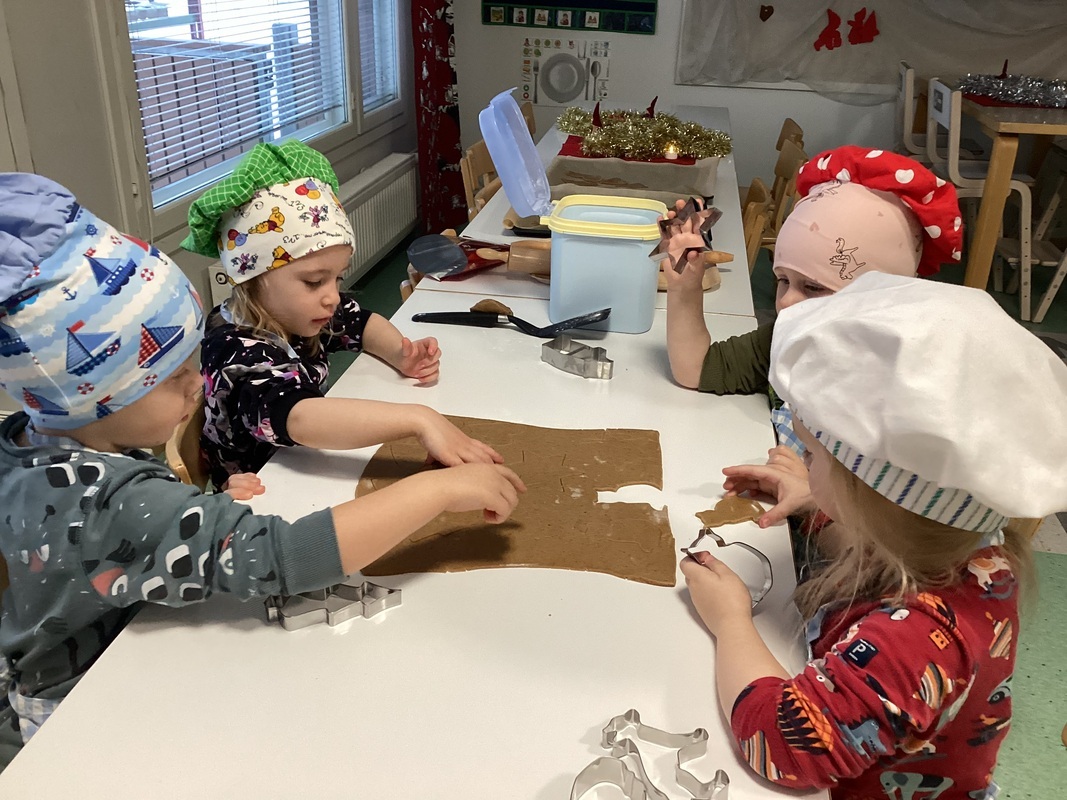 Kuvassa neljä lasta leipoo joulupipareita.