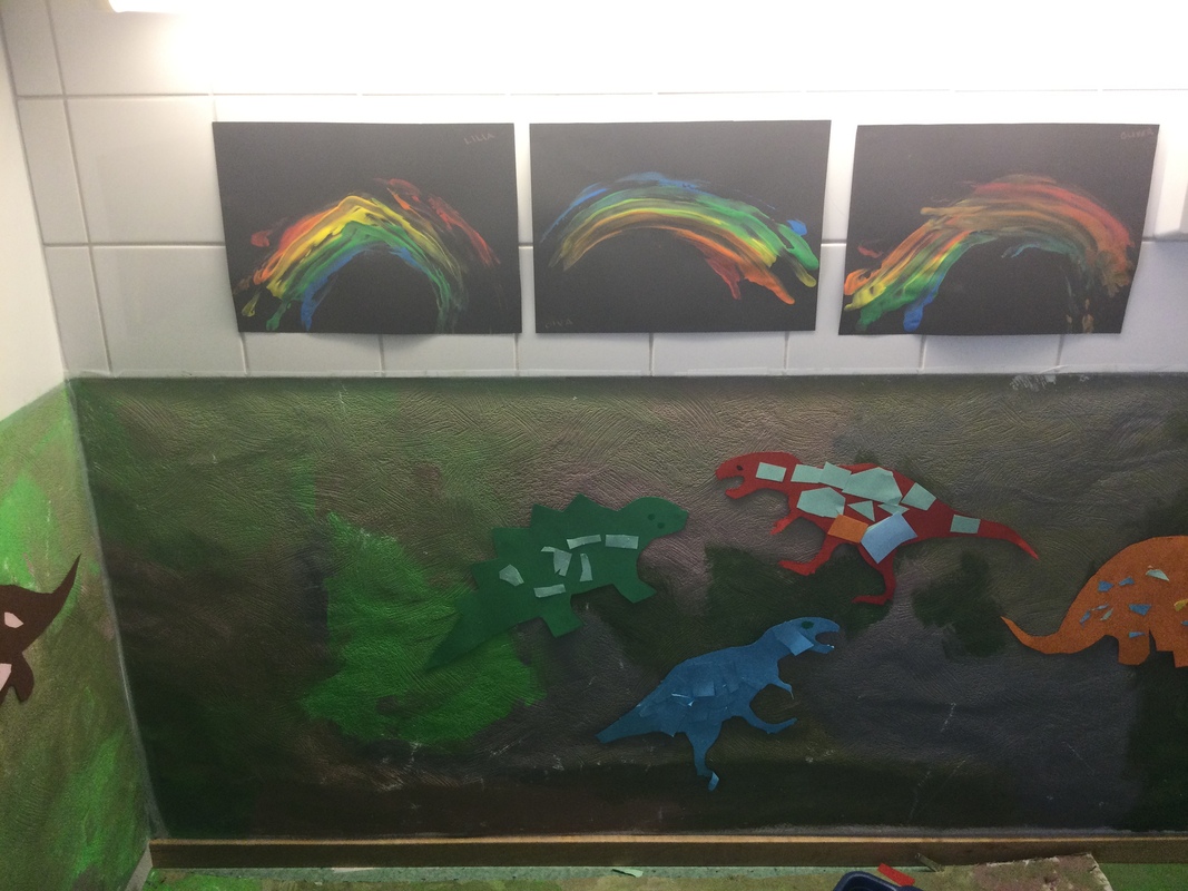Kuvassa seinä, jossa on maalattu paperi seinässä ja siihen on laitettu lasten askartelemia dinoja.