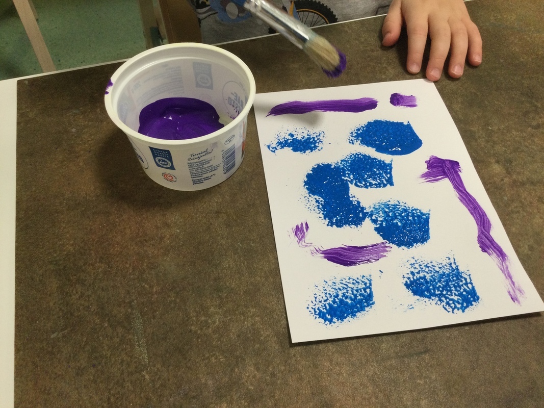 Kuvassa lapsen tekemä maalaus, maalikippo ja sivellin.