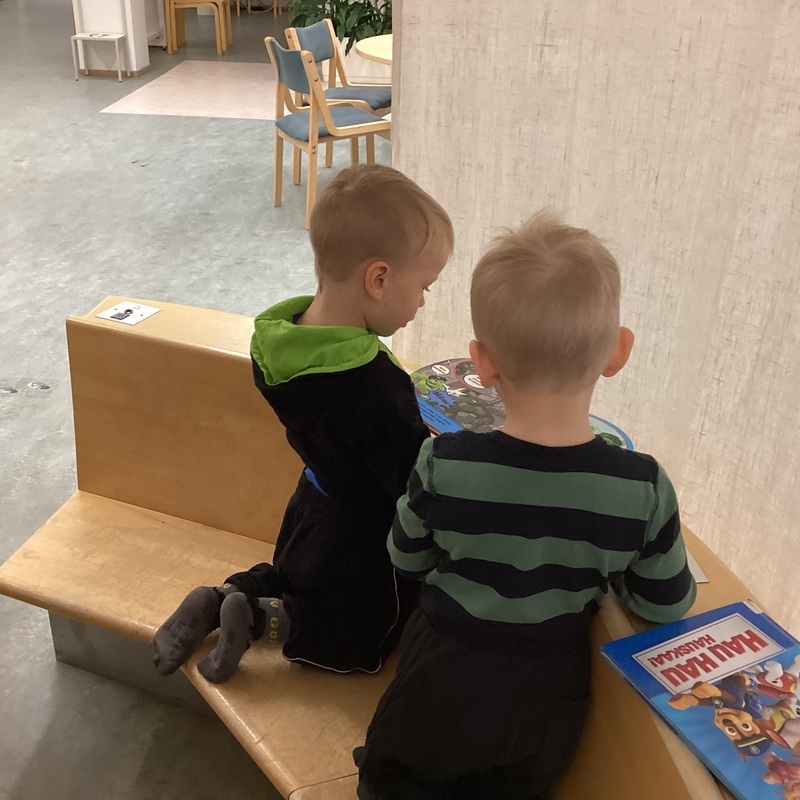 Kuvassa kaksi lasta lukevat kirjaa kirjastossa.