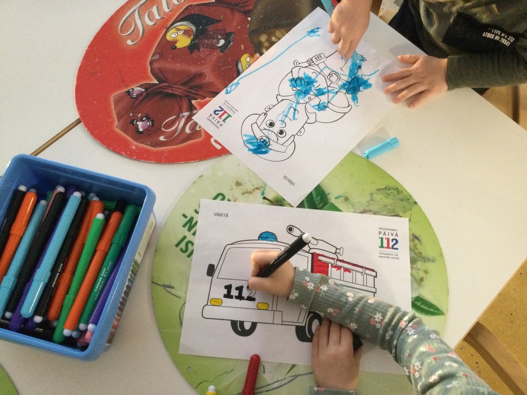 Kuvassa näkyy kahden lapsen kädet, jotka värittävät värityskuvia tusseilla.