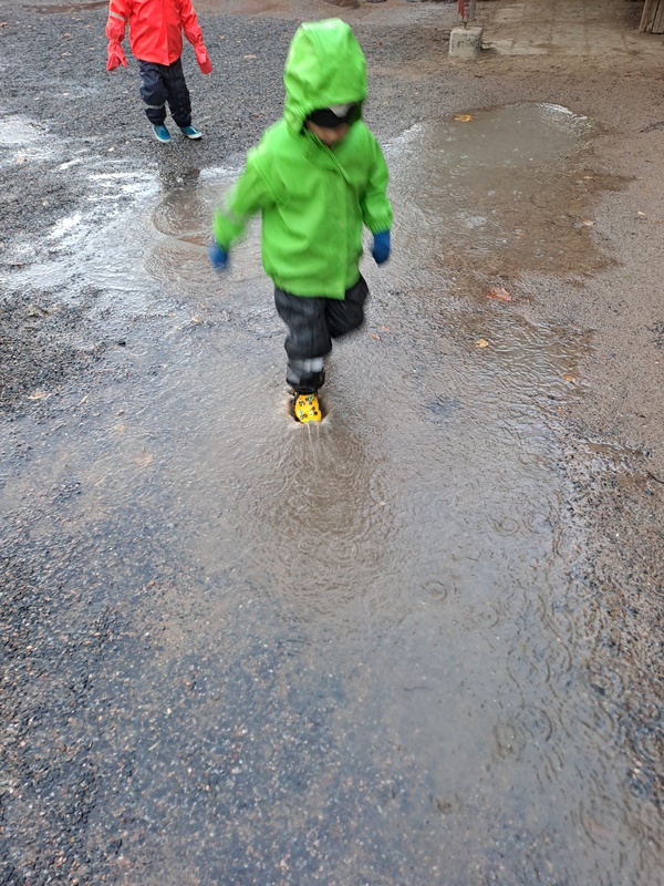 Lapsi juoksee vesilätäkössä.
