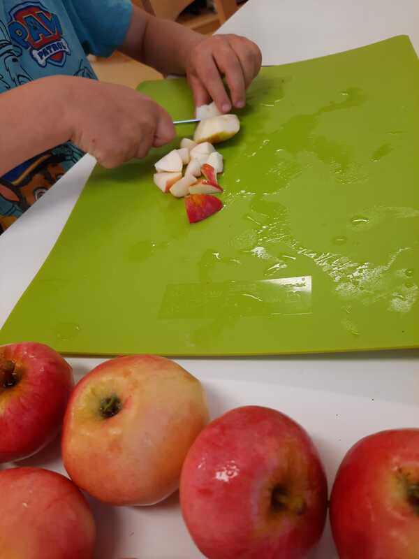 Lapsi pilkkoo veitsellä omenaa.