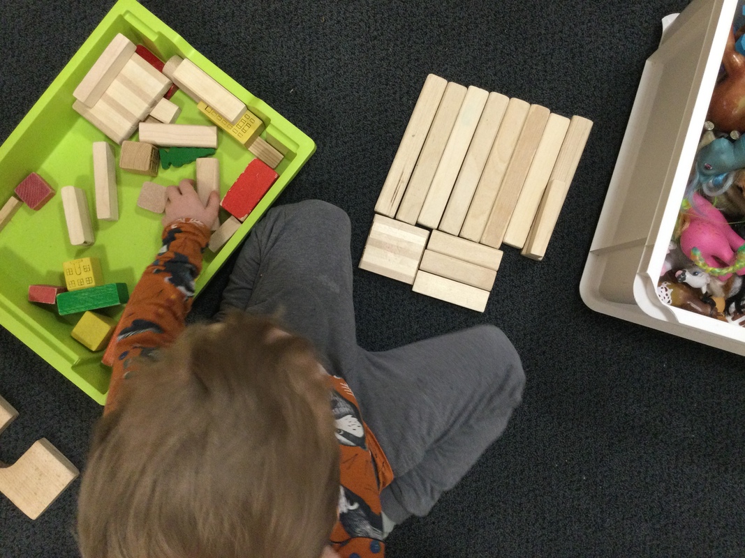 Kuvassa lapsi rakentaa puupalikoilla