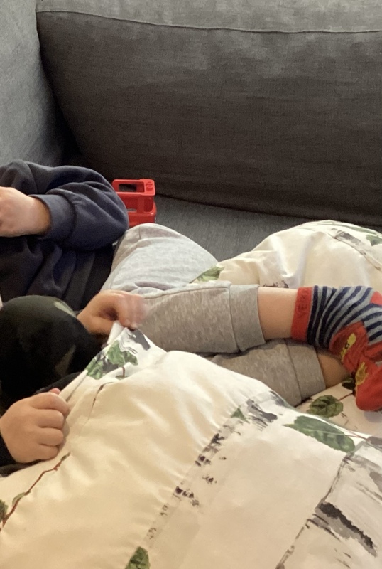 Kuvassa kahden lapsen jalat sohvatyynyn päällä