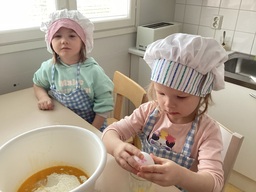 Lapset leipomassa, tyttö rikkoo kananmunaa.